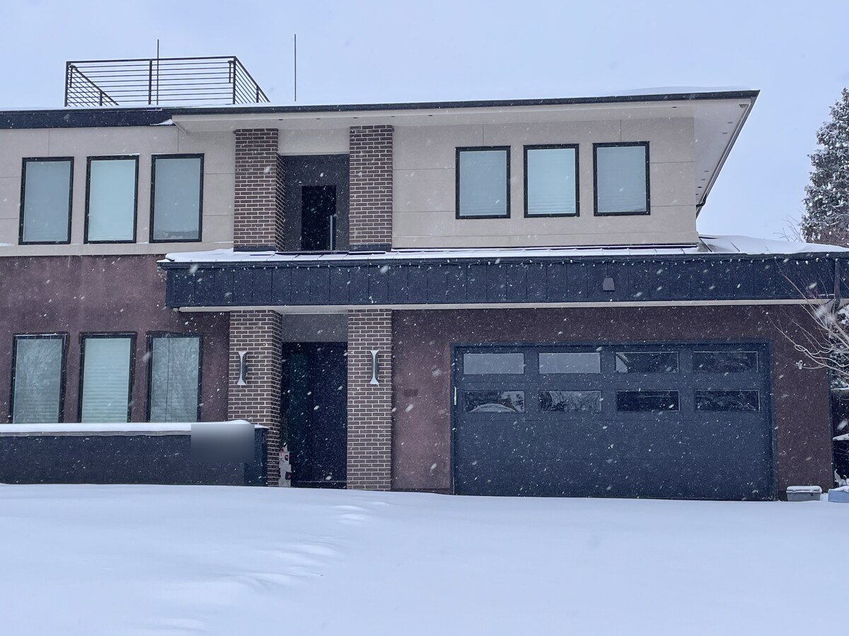 Modern dark-framed garage door with horizontal glass panels installed on a Denver home in winter