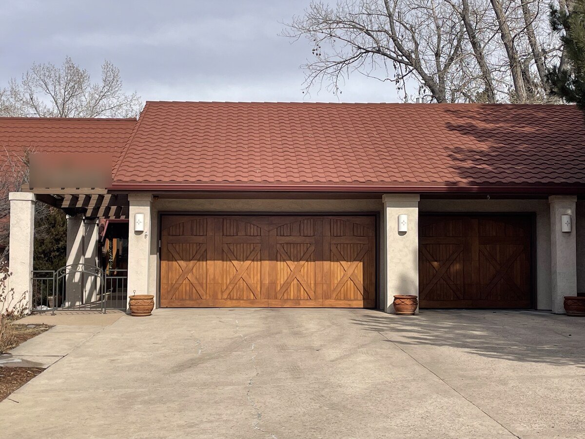 Two wood-look carriage-style garage doors installed on a red tile roof home in Greenwood Village